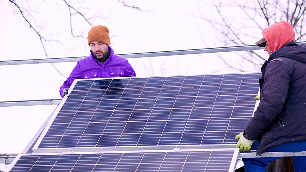 Instalação de placas solares no inverno por técnicos agasalhados, mostrando que o sistema funciona mesmo com frio.