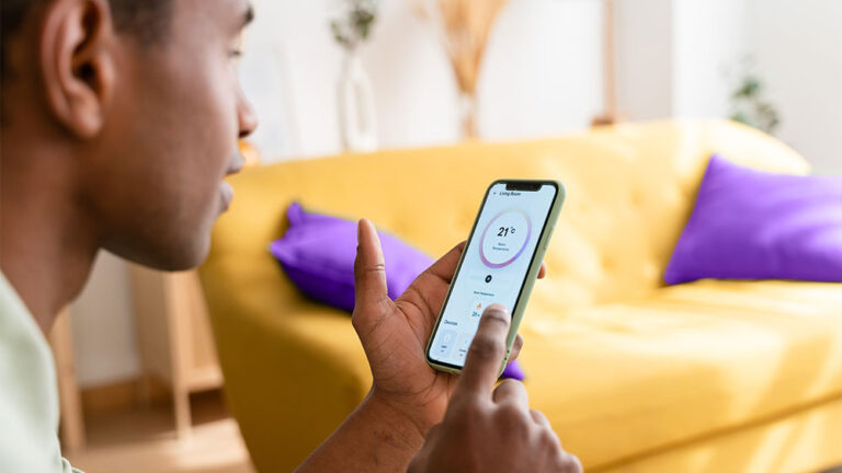 Pessoa usando aplicativo de automação residencial no celular, ajustando a temperatura da casa com tecnologia inteligente, representando a Revolução Tecnológica no consumo de energia.